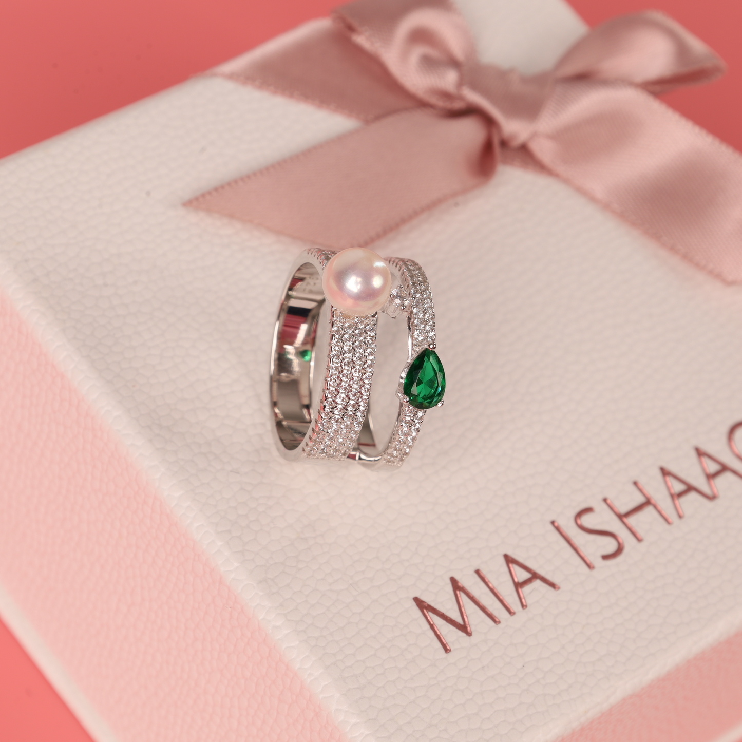 The Green Cubic Zirconia Pearl Ring by Mia Ishaaq is elegantly presented in a white gift box wrapped with a pink ribbon.