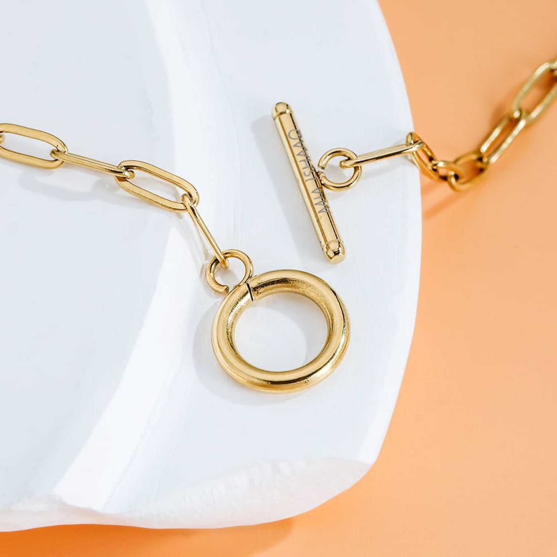 T-bar link chain gold necklace on peachy background - Mia Ishaaq