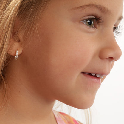 Child model wearing 925 sterling silver, 14k gold-plated earrings, shot from the side, highlighting the earrings hugging the ear - Mia Ishaaq