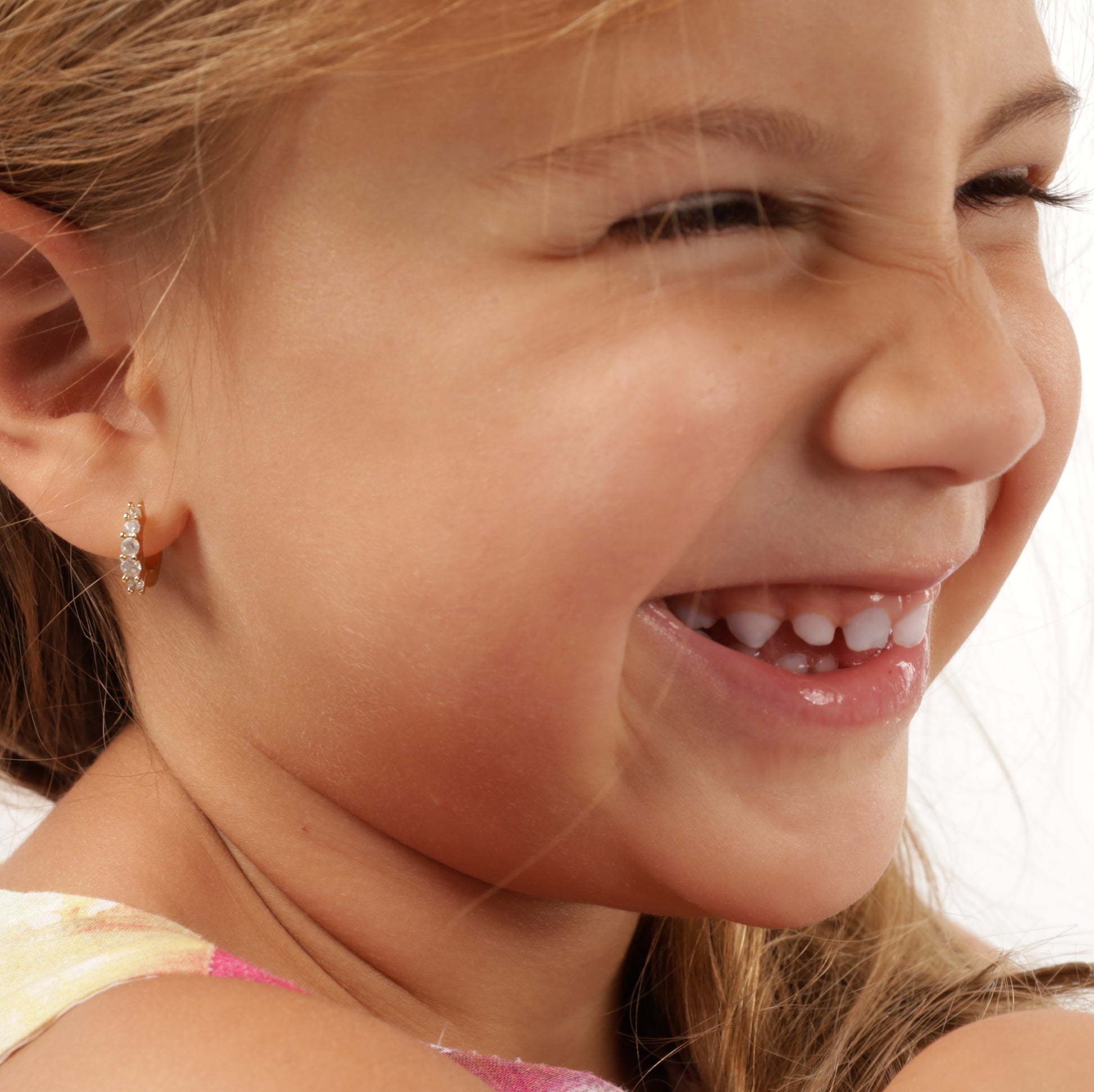 Child model with a cheeky smile wearing 925 sterling silver, 14k gold-plated earrings, capturing the playful essence of the design - Mia Ishaaq