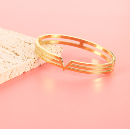 This minimalist jewellery piece, the Gold V Line Harmony Bangle Bracelet by Mia Ishaaq, is crafted with an 18k gold-plated finish and features geometric cut-out designs.