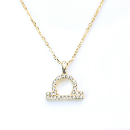 Celestial necklace featuring a gold chain and diamond-encrusted Aquarius zodiac symbol pendant by Mia Ishaaq, set against a white background.