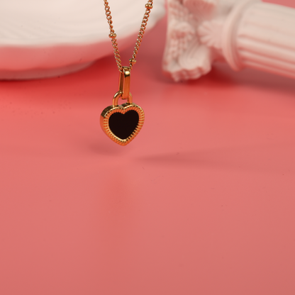 Hanging from the top down Gold water-resistant reversible enamel heart pendant beaded chain necklace on a pink background - Mia Ishaaq