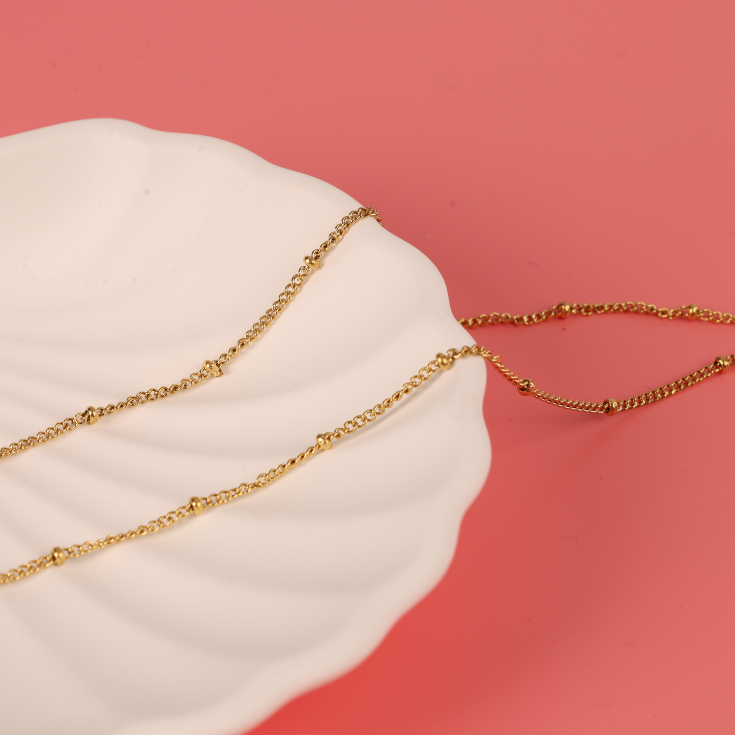 Mia Ishaaq® Enamel Heart Reversible Necklace elegantly displayed on a white scalloped dish against a pink backdrop, highlighting its versatile style.