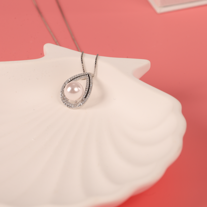 A Pearl Pendant Crystal Necklace by Mia Ishaaq rests elegantly on a white plate.