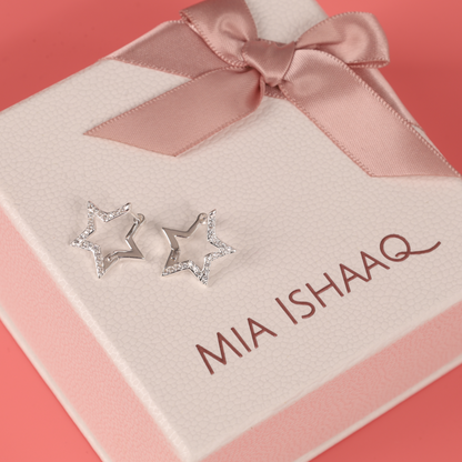 The stunning Sparkly Star Huggie Hoop Earrings from Mia Ishaaq, made of 925 sterling silver and embellished with cubic zirconia, are gracefully presented in a textured gift box featuring a pink ribbon and the text "MIA ISHAAQ.