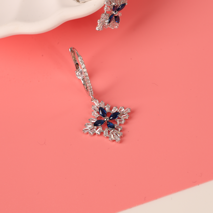 Mia Ishaaq's Blue Spinel CZ Earrings made of 925 Sterling Silver elegantly showcased on a pink and white surface.