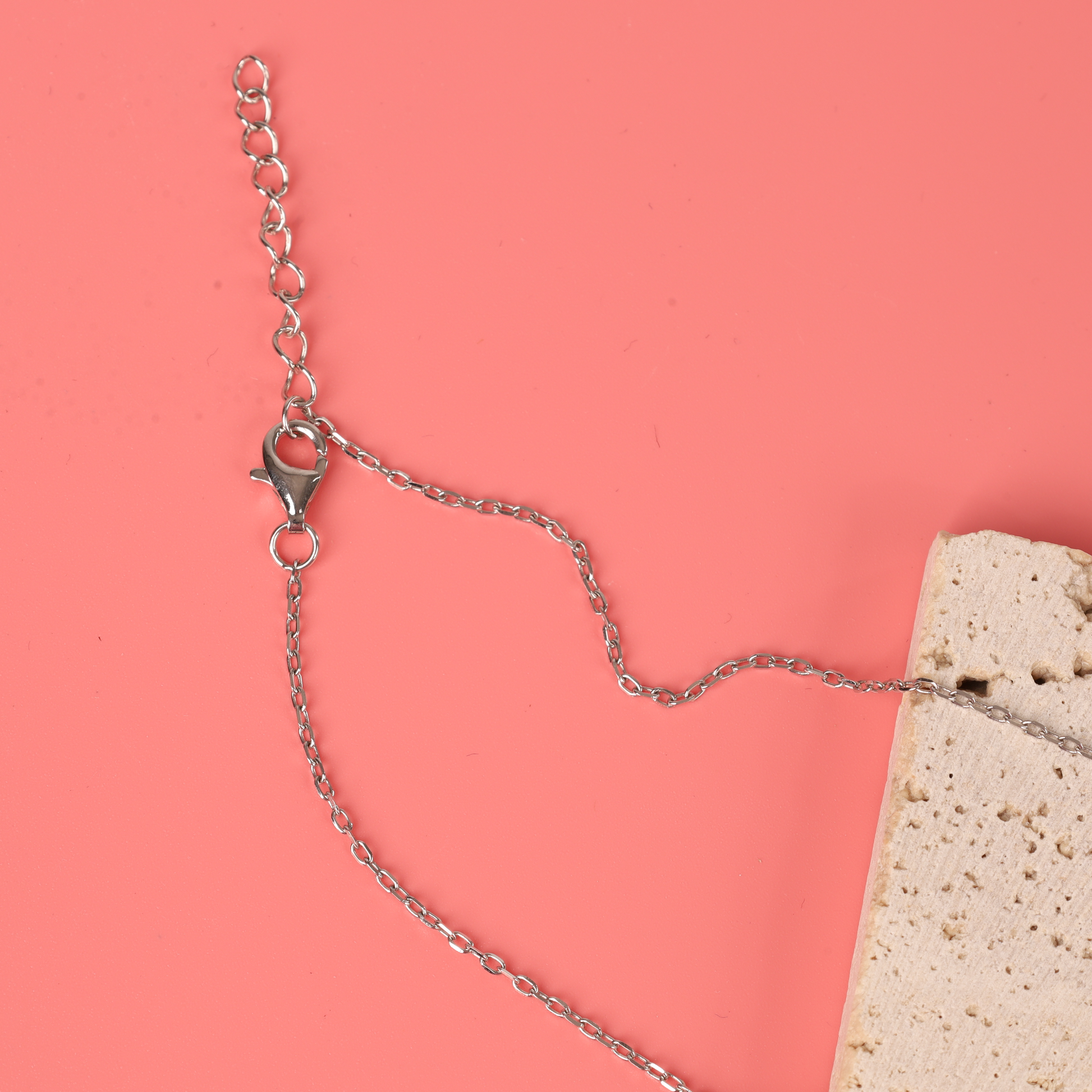 Close up of the clasp and chain design of the 925 sterling silver interlocking circle eternity friendship necklace on a pink background - Mia Ishaaq