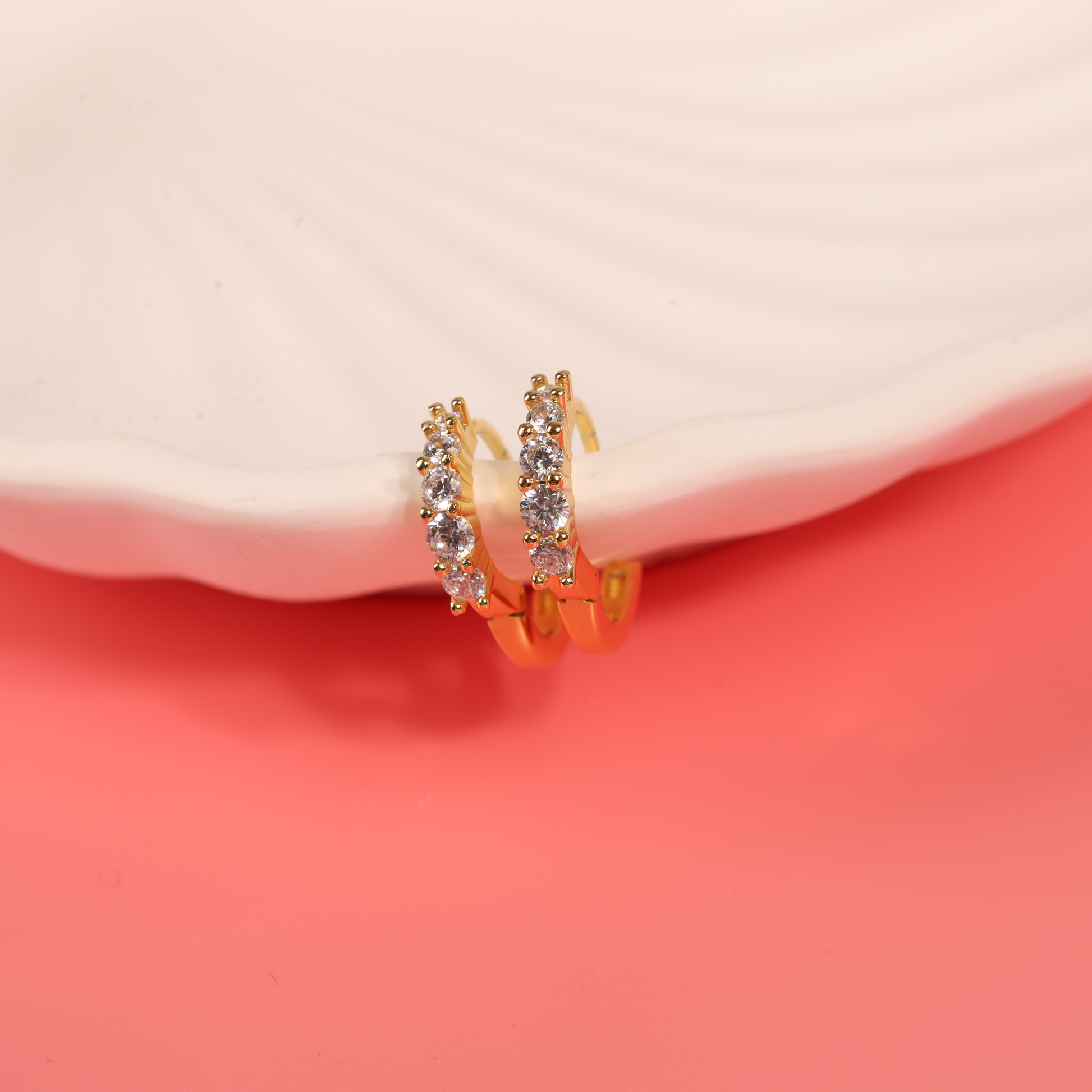 925 sterling silver, 14k gold-plated earrings with cubic zirconia clipped on the edge of a shell-shaped bowl, facing front to highlight their delicate design and sparkling details - Mia Ishaaq