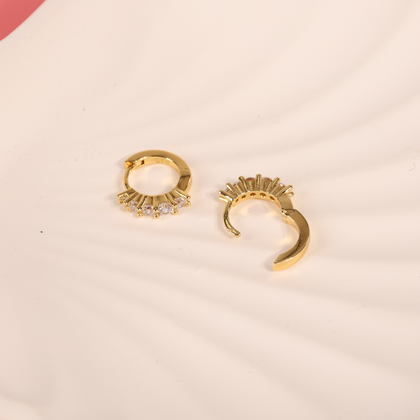 Top-down view of 925 sterling silver, 14k gold-plated earrings with cubic zirconia on a white background, showcasing one earring opened to reveal the secure closure design - Mia Ishaaq