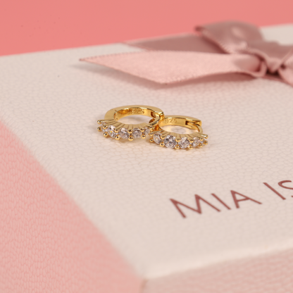 Front view of 925 sterling silver, 14k gold-plated earrings with cubic zirconia, elegantly laid over one another on top of our signature gift boxes, highlighting their sleek design - Mia Ishaaq