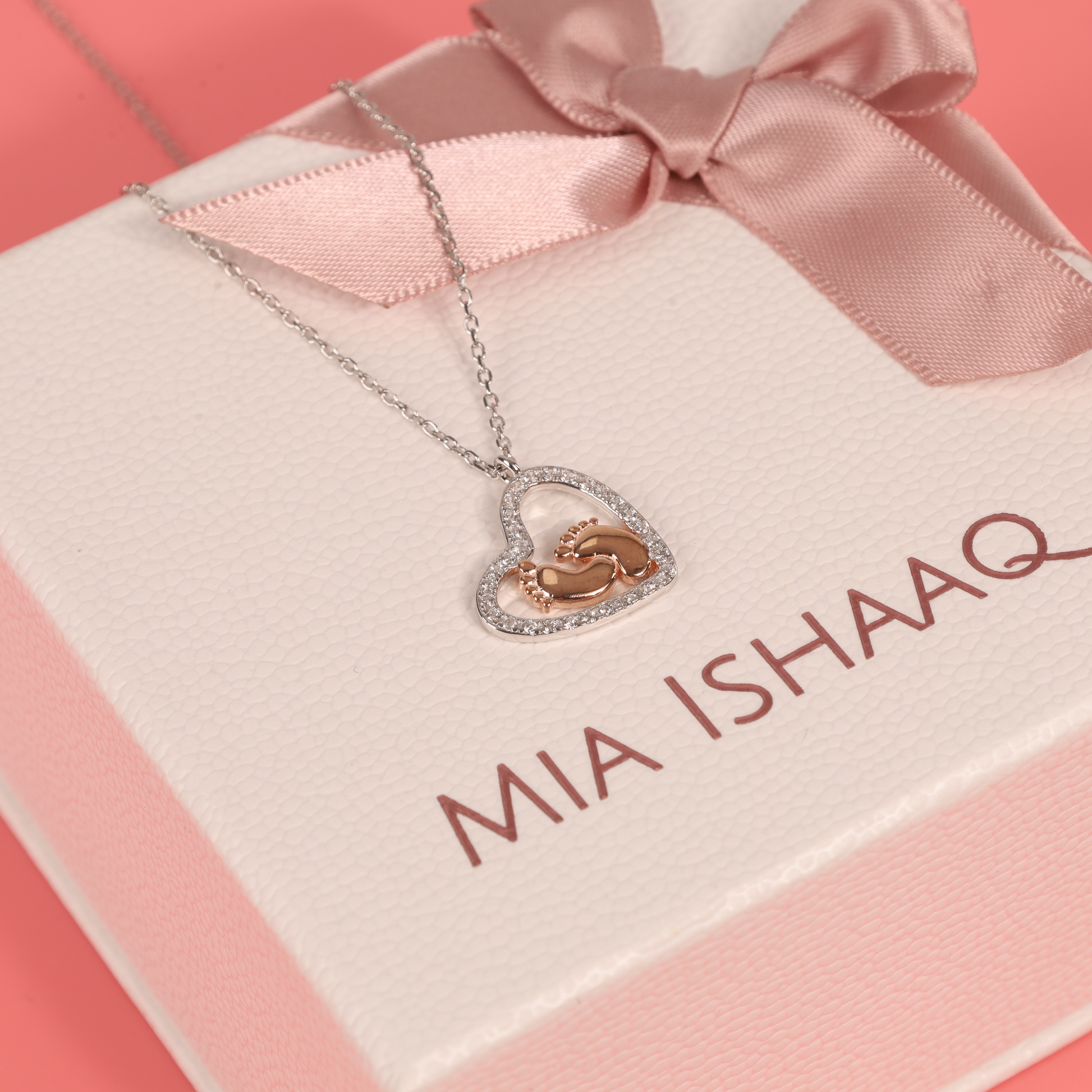 Sterling Silver Cubic Zirconia Mothers Love Heart Pendant with baby footprints necklace displayed on the top of our signature gift box - Mia Ishaaq