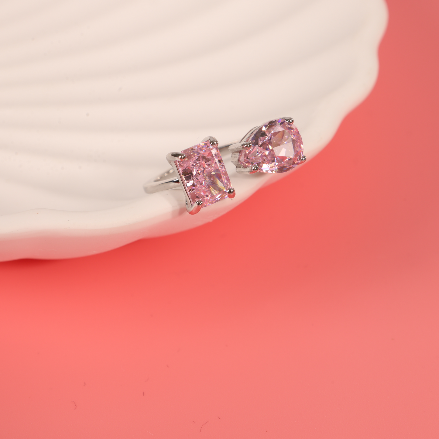 Sterling silver open ring with pink cubic zirconia placed on a white ceramic bowl against a pink background - Mia Ishaaq