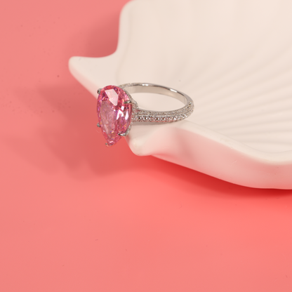 Blush Drop Elegance Ring highlighted on a light pink background, surrounded by white pearls to enhance its luxurious look - Mia Ishaaq