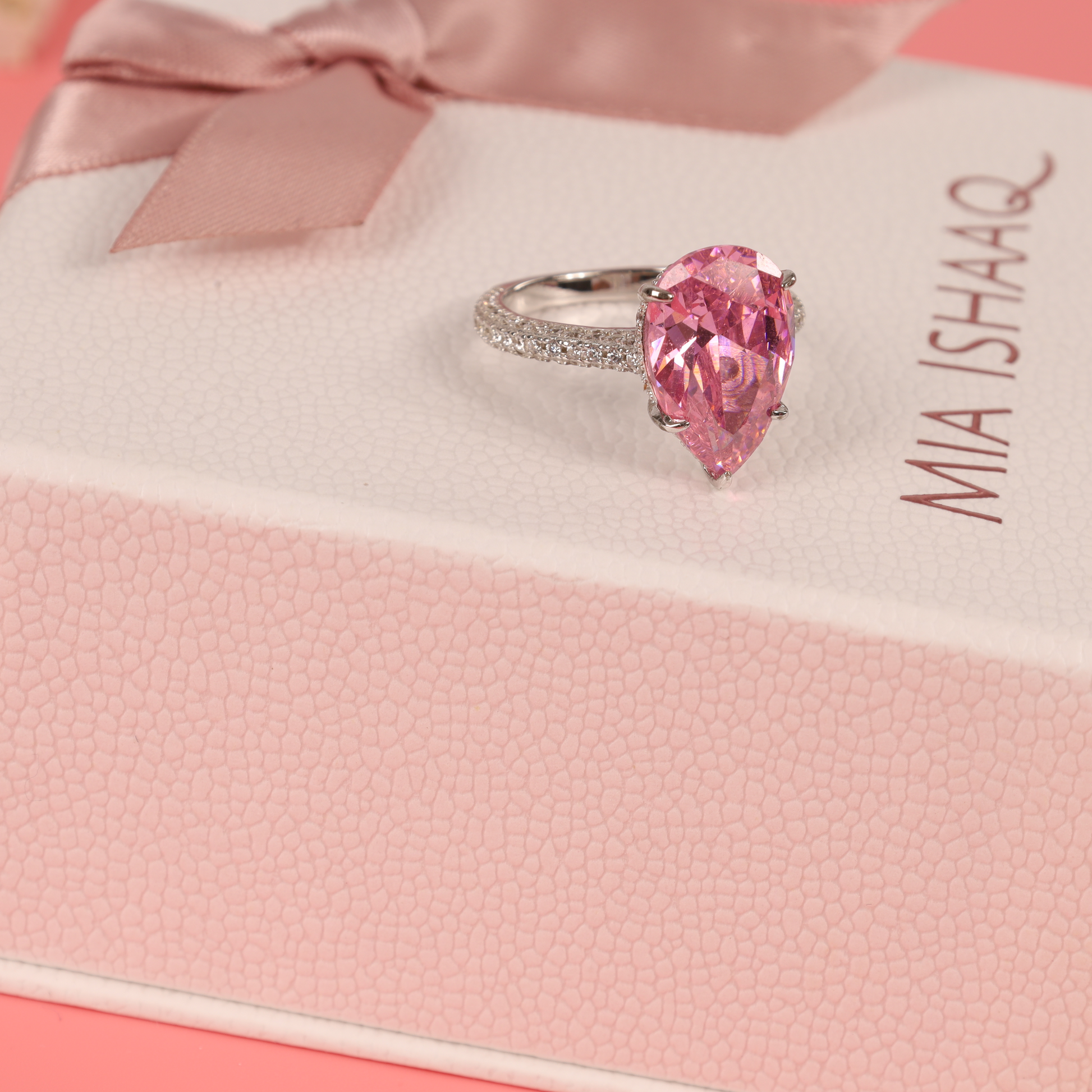 A beautifully styled shot of the Blush Drop Elegance Ring on a soft pink background, paired with white lace for a delicate and feminine touch - Mia Ishaaq