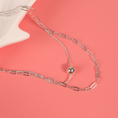 Sterling silver layered necklace displayed on a pink background inside a white ceramic shell-shaped bowl, accentuating its intricate design - Mia Ishaaq