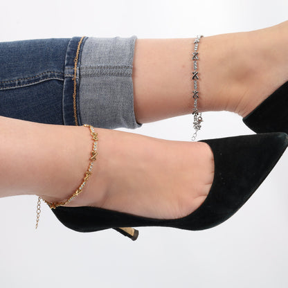 Two legs wearing cuffed jeans with black heels, adorned with a Mia Ishaaq Gemma XO Crystal Cross Anklet in silver and gold anklets.