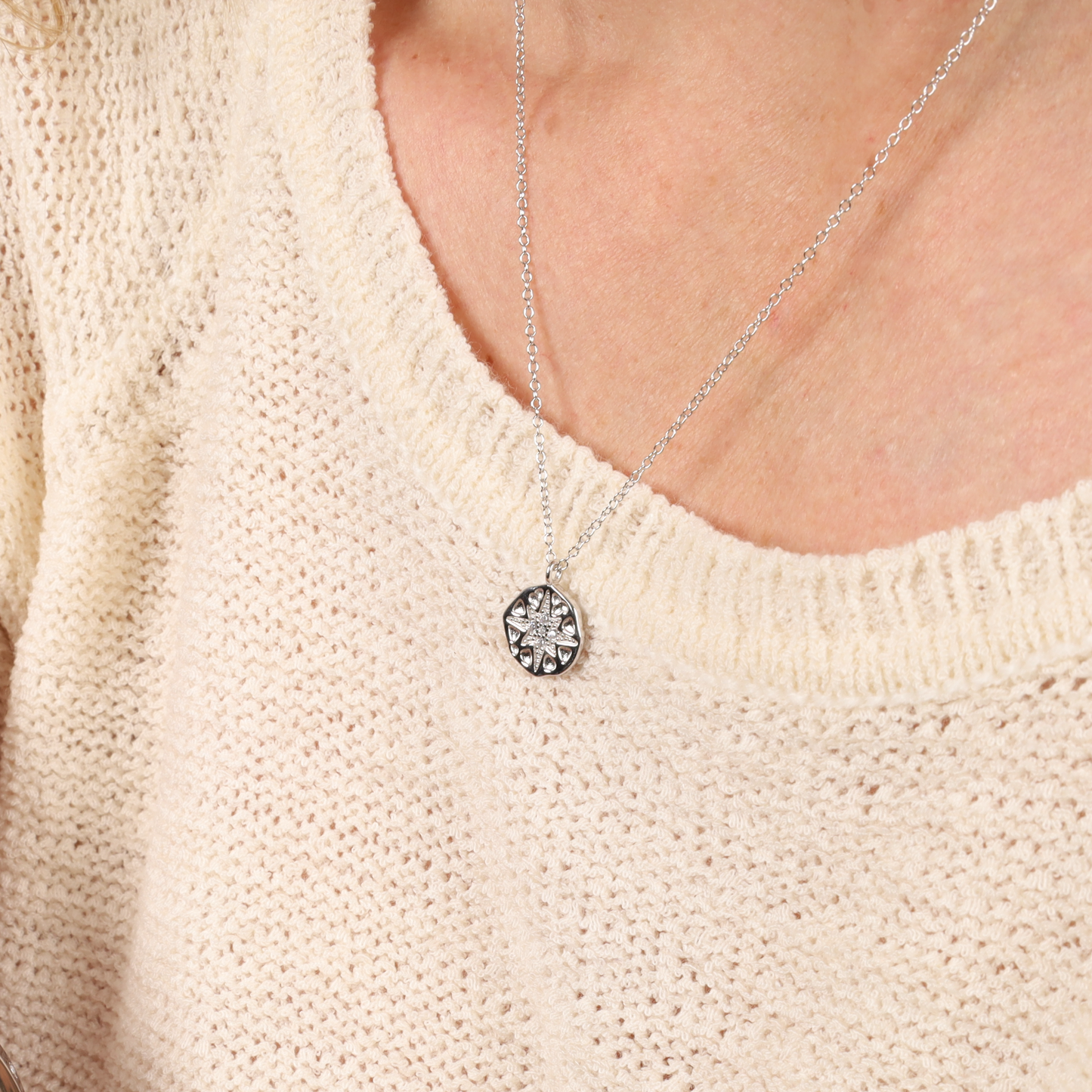 A person wearing a cream sweater and a Mia Ishaaq® Polaris Coin Pendant Necklace in sterling silver.