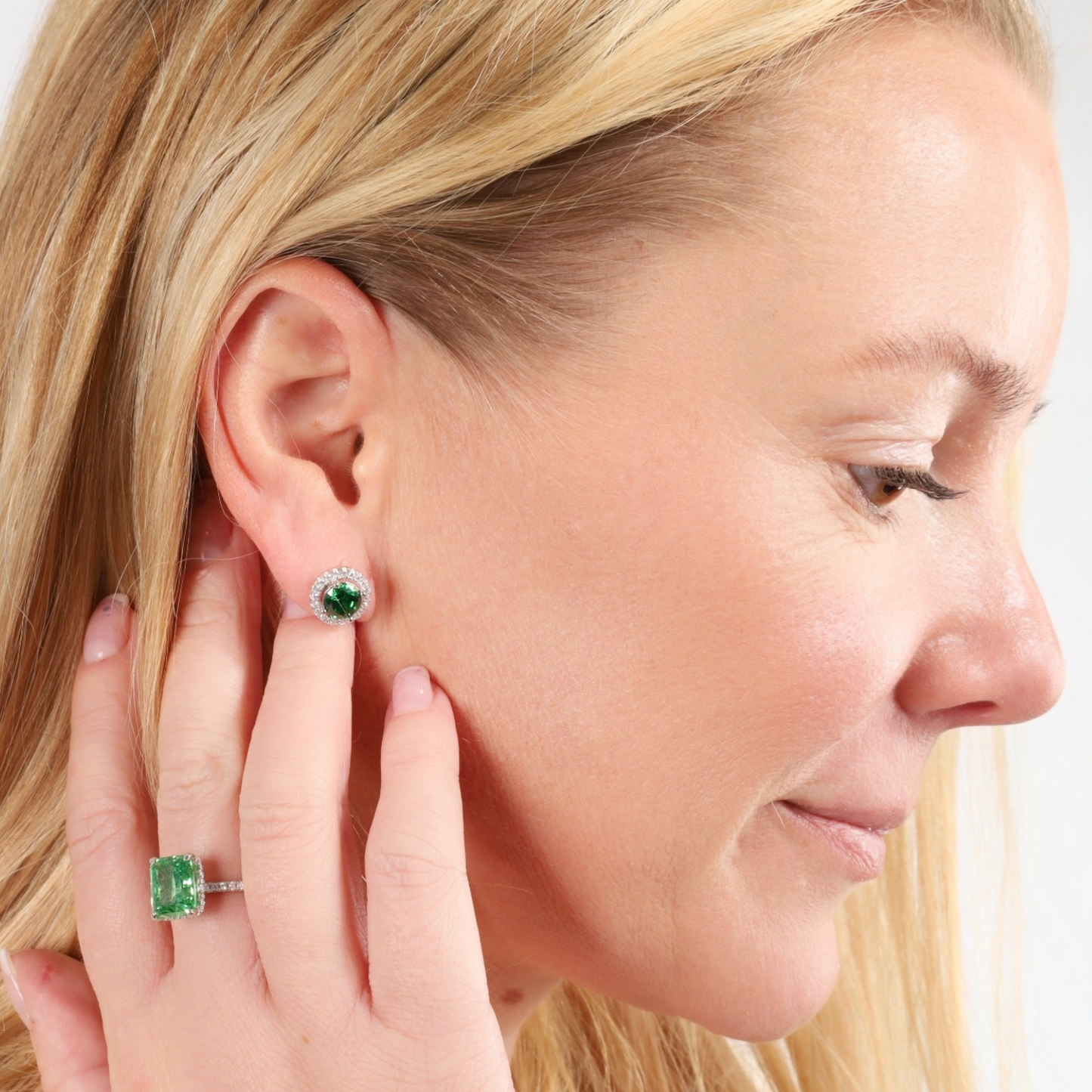 A woman is adorned with the Emerald Glow Radiant Studs by Mia Ishaaq and an emerald ring, showcased in a close-up side profile. The intricate design of this Nature-Inspired Jewellery complements her look beautifully, highlighting the elegance of the 925 Sterling Silver Earrings she wears.