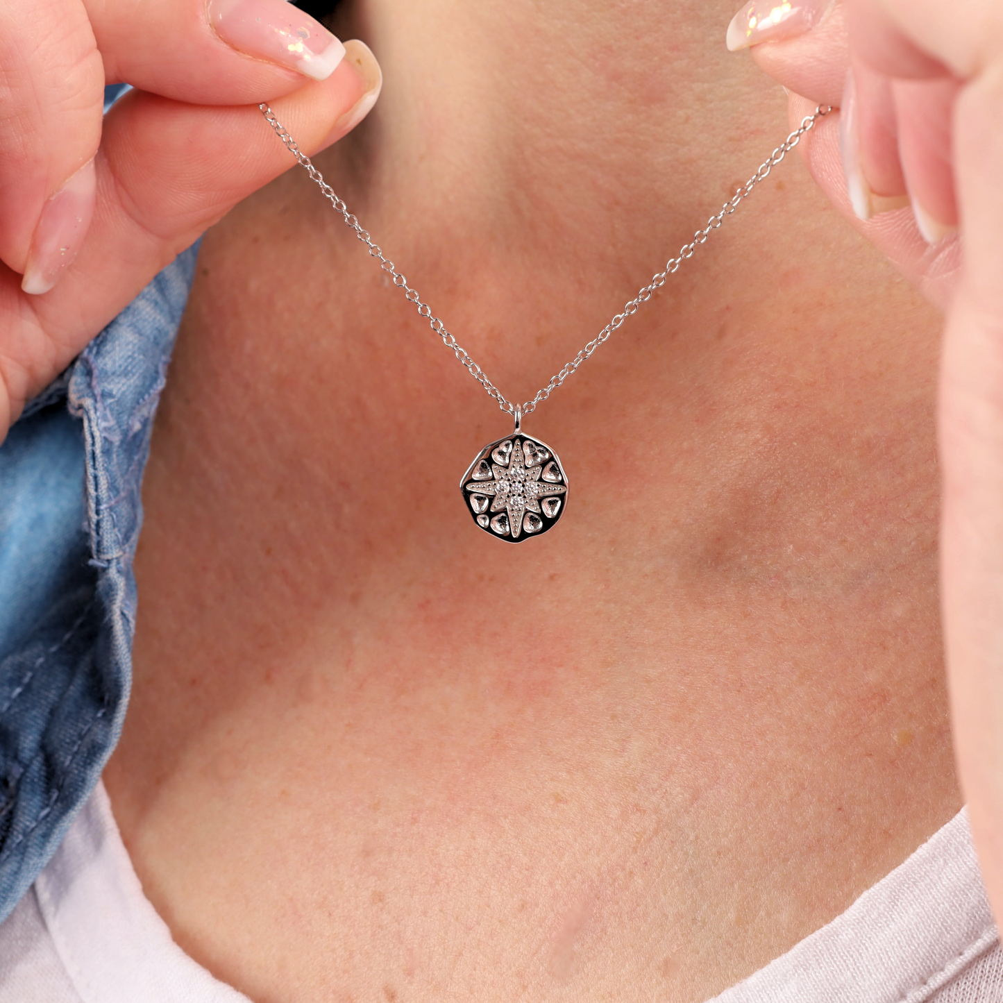 Close-up of a person holding the Mia Ishaaq® Polaris Coin Pendant Necklace in sterling silver.