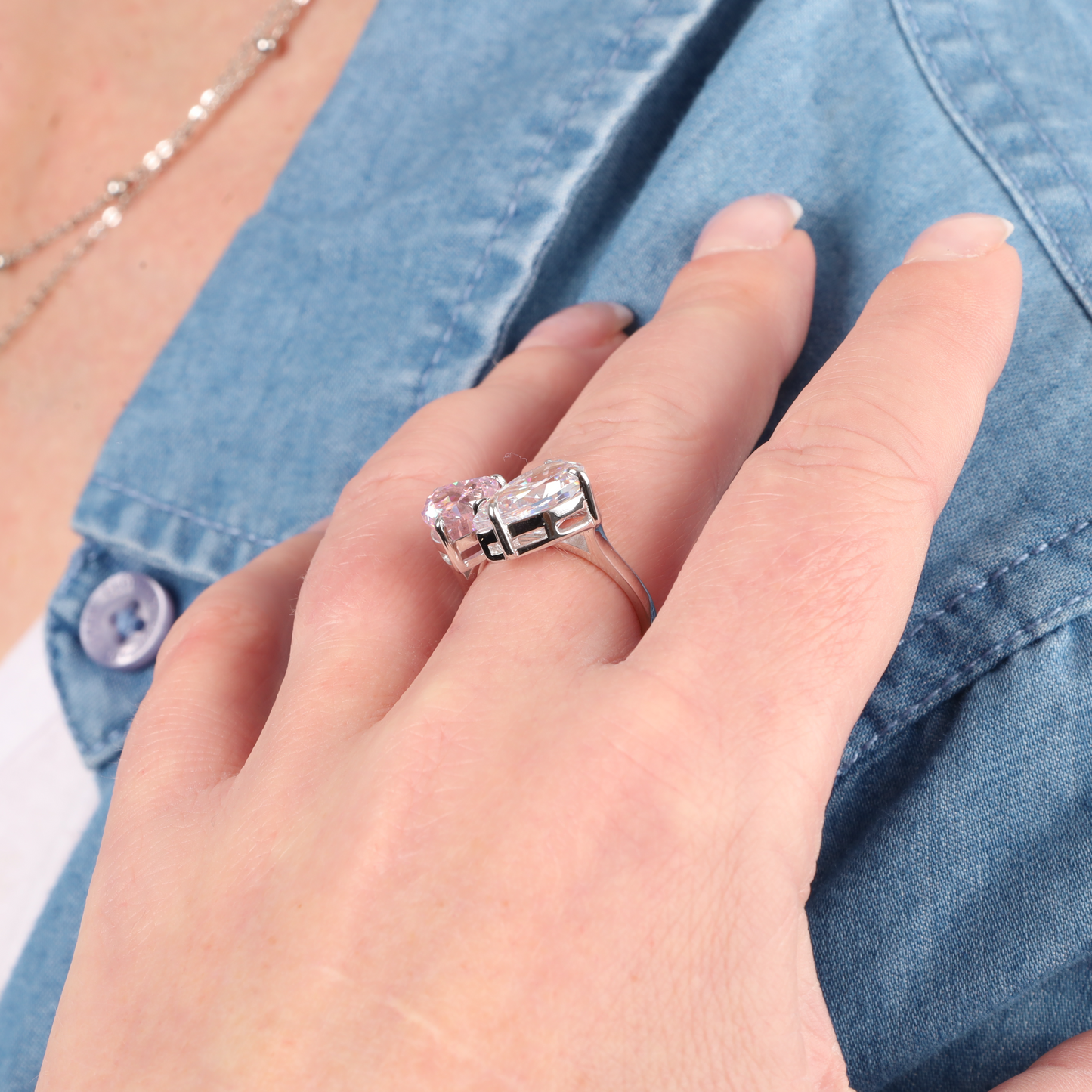 A hand adorned with the Mia Ishaaq Sterling Silver Radiant Duo Ring - adjustable, featuring large cubic zirconia stones, rests elegantly on a denim shirt.