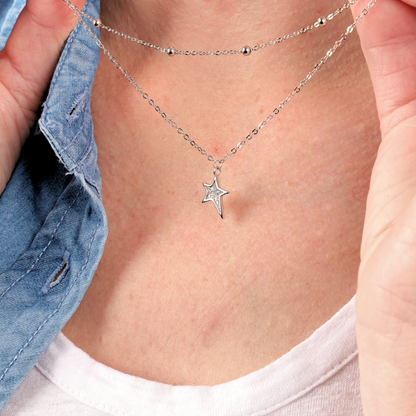 Close-up of a person wearing the Mia Ishaaq Star Pendant Layered Celestial Necklace, showcasing a star-shaped pendant crafted from sterling silver.