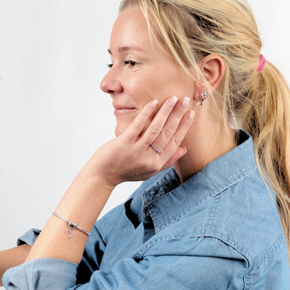 Side face shot of model wearing a silver bracelet with heart-shaped dog memorial charm, featuring pink cubic zirconia paw print detail - Mia Ishaaq