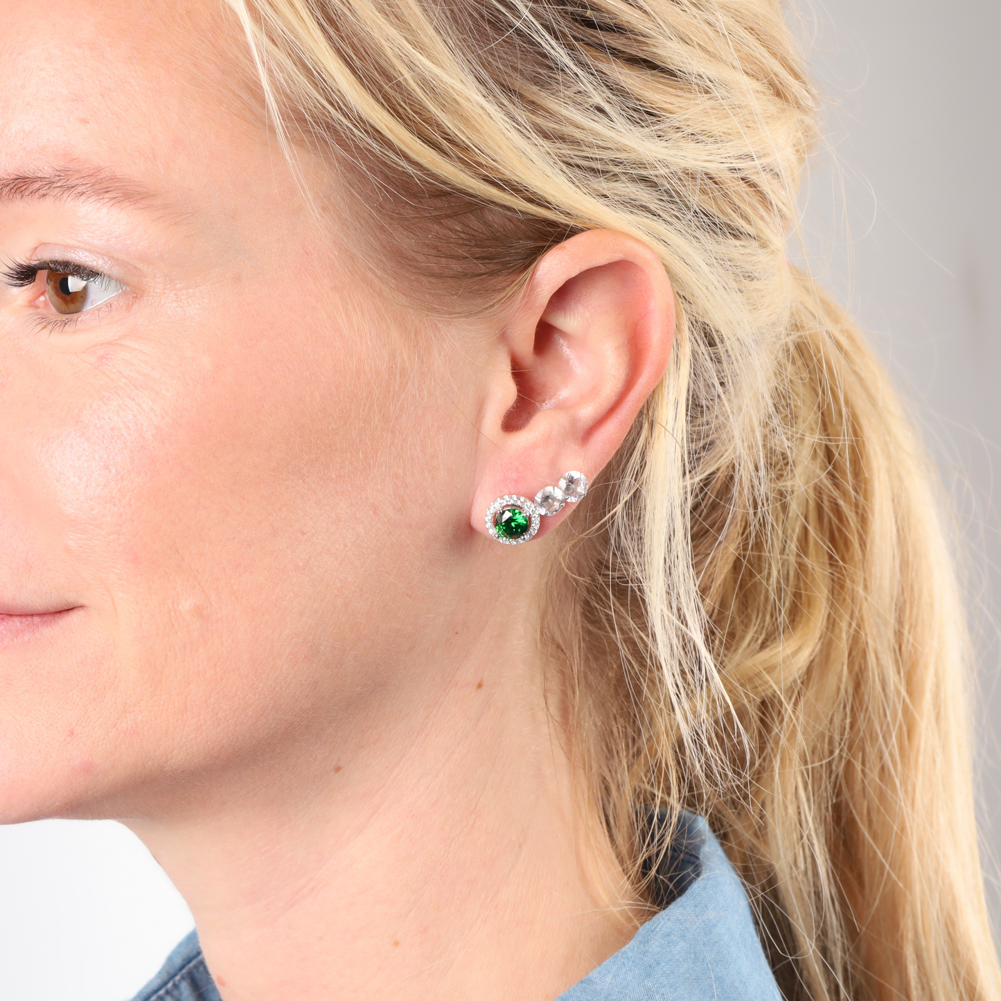 Profile of a person with blonde hair wearing the elegant Emerald Glow Radiant Studs by Mia Ishaaq, featuring 925 Sterling Silver and green accents that capture the essence of nature-inspired jewelry.