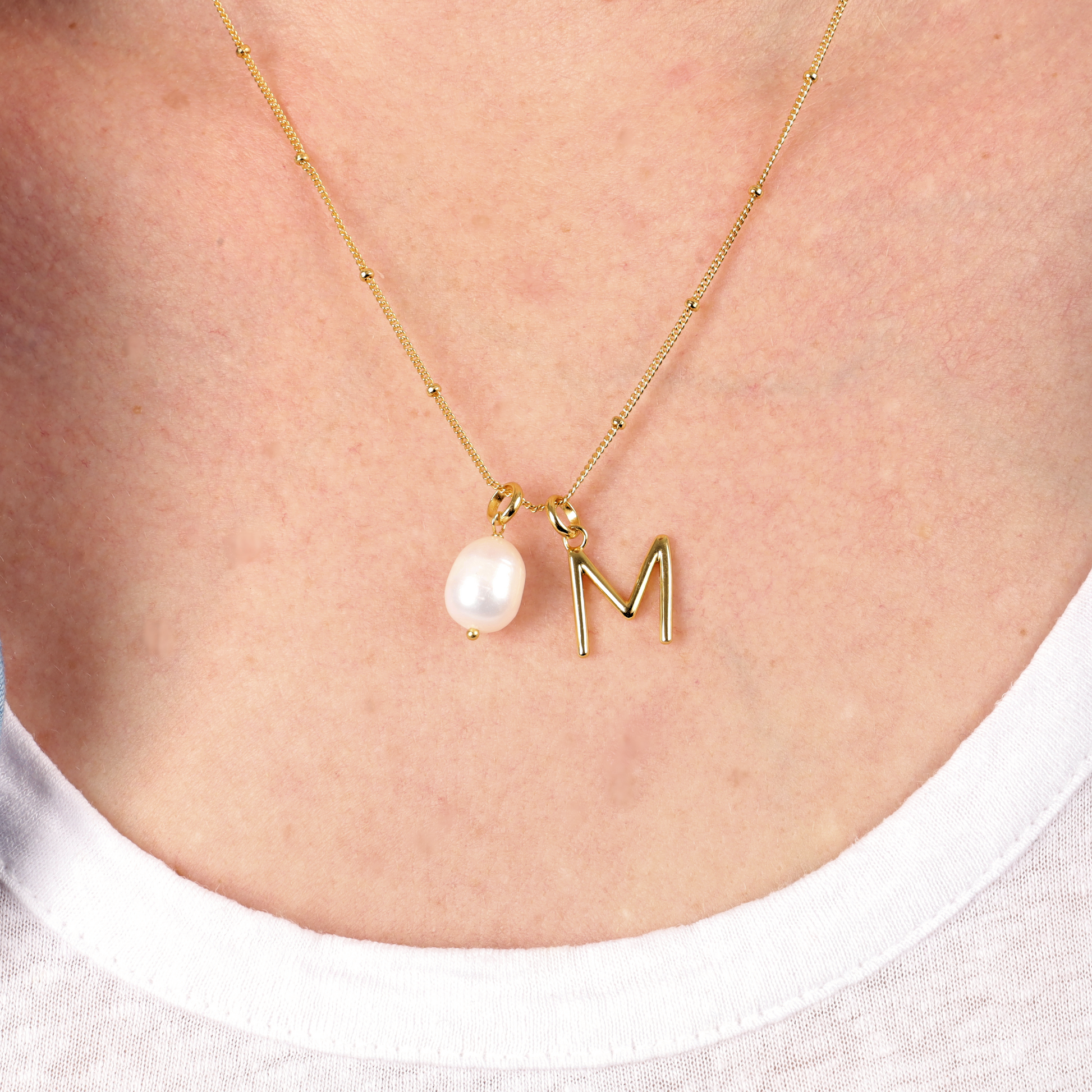 Gold Vermeil Pearl Pendant Initial Necklace from Mia Ishaaq elegantly showcases a pearl pendant alongside an "M" charm, embodying the essence of personalization.