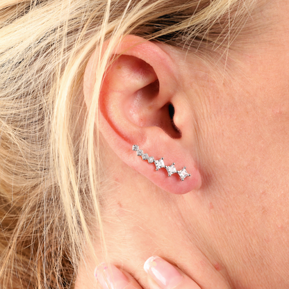 Close-up of an ear adorned with a Mia Ishaaq Crystal Ear Cuffs Earring, elegantly crafted from 925 sterling silver and featuring a row of star-shaped stones.