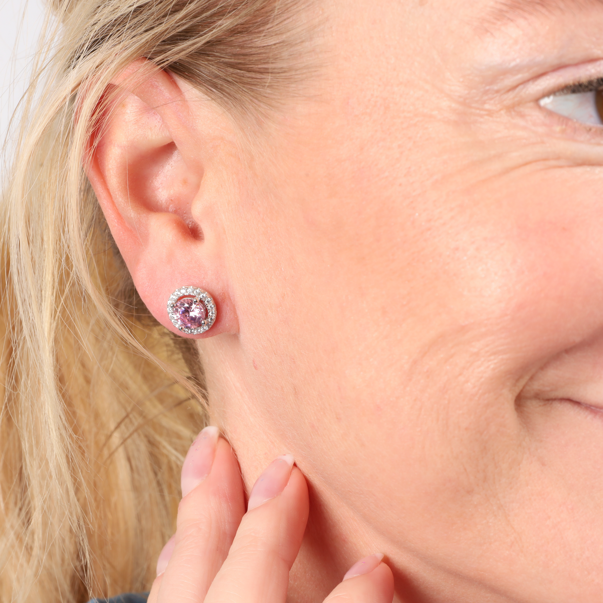 Close-up of a person wearing Mia Ishaaq's 925 Sterling Silver PINK CZ Stud Earrings, gently touching their neck and smiling softly.