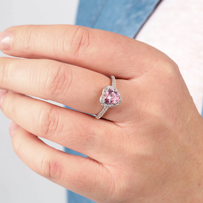 A hand adorned with the Sterling Silver HALO Heart Ring by Mia Ishaaq, featuring a pink gemstone and shimmering cubic zirconia accents.