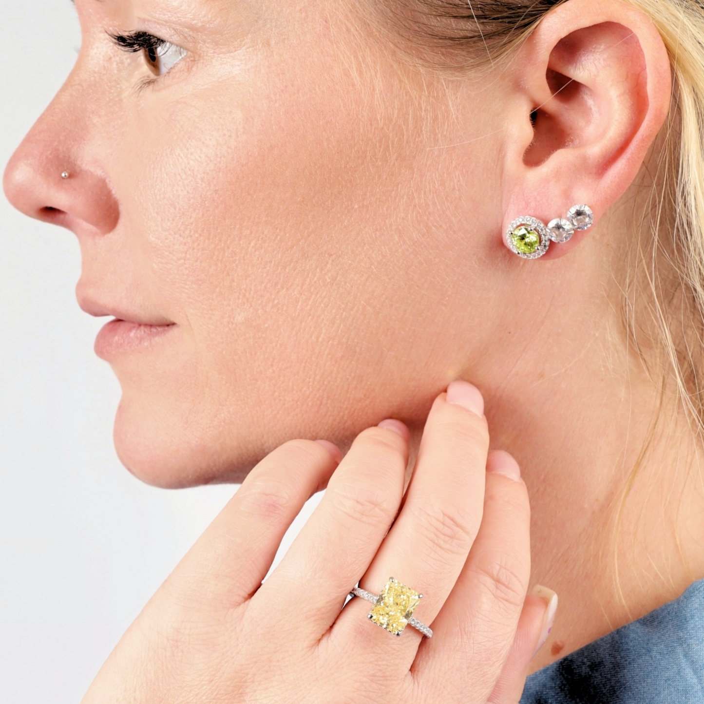 A woman wearing the Apple Blossom Radiant Studs by Mia Ishaaq and a ring with a yellow gemstone.