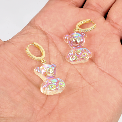 Hand displaying the Shimmering Teddy Bear Earrings by Mia Ishaaq, featuring gold hoops embellished with cubic zirconia.