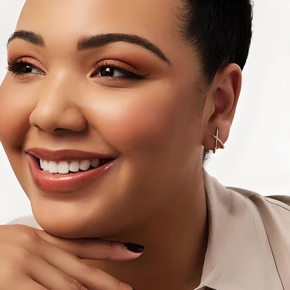 Headshot of a young short haired model smiling wearing a Gold Cross Sparkle Stud Earrings with cubic zirconia - Mia Ishaaq