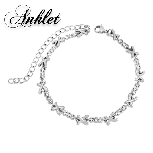 Mia Ishaaq's Gemma XO Crystal Cross Anklet in silver showcases a stainless steel design with X-shaped and circular links, beautifully displayed against a white background.